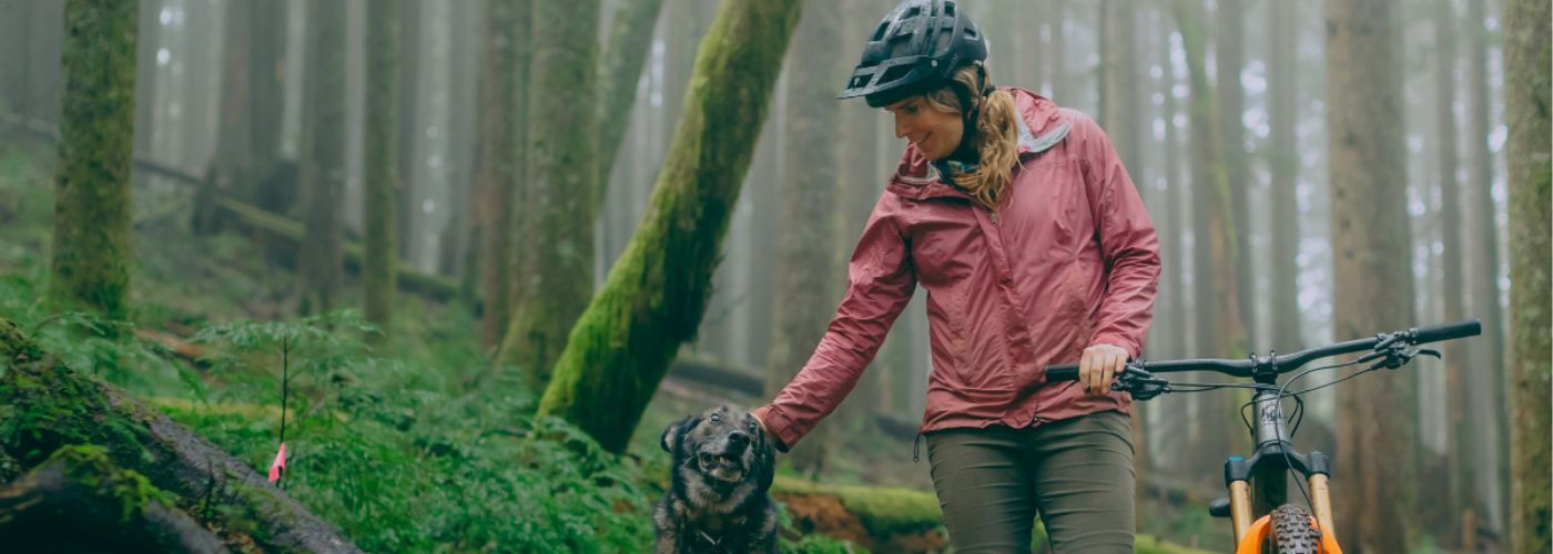 alex with her bike and dog in a foggy, mossy wood