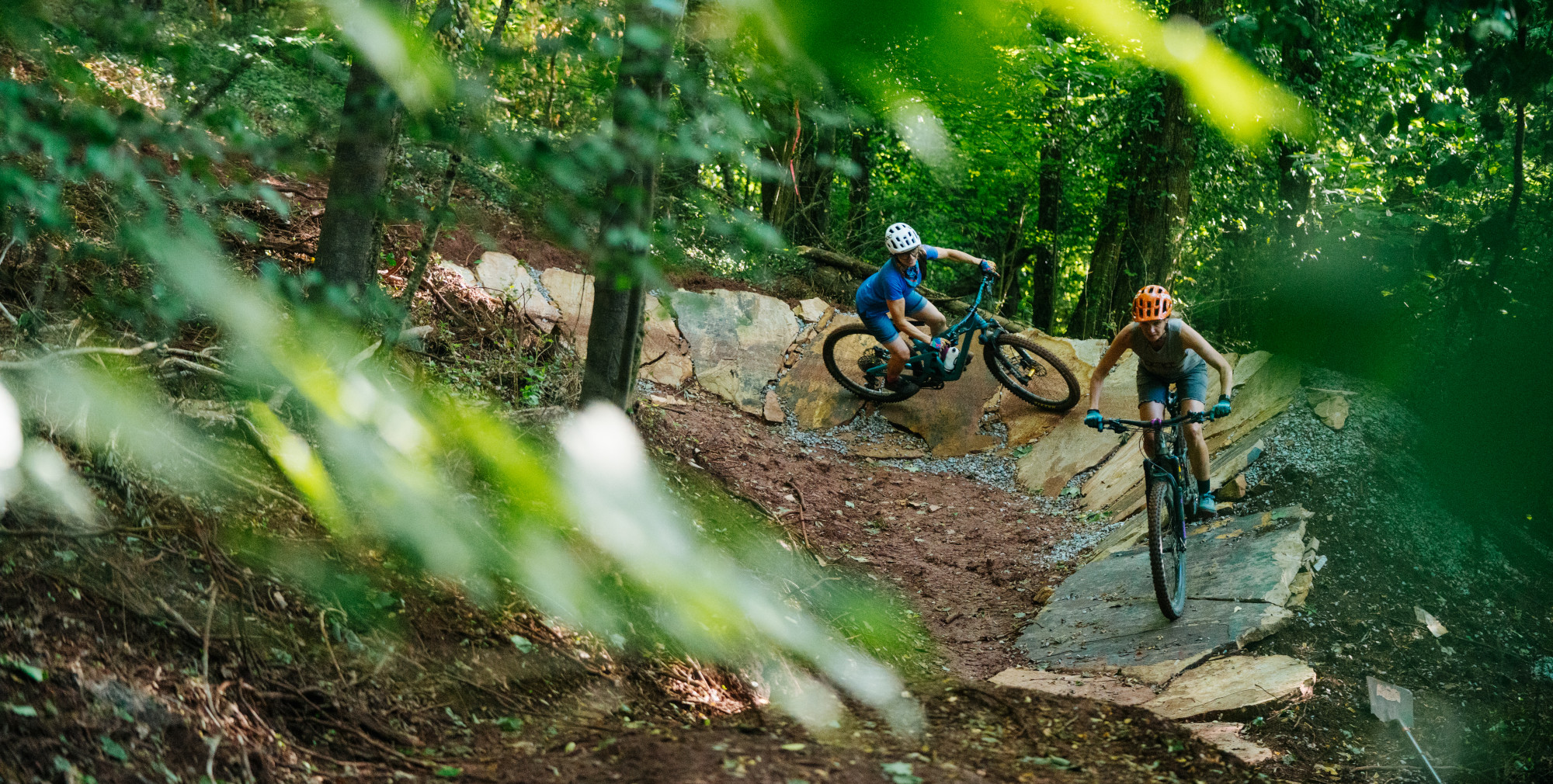 two MTB riders round a rock armored berm
