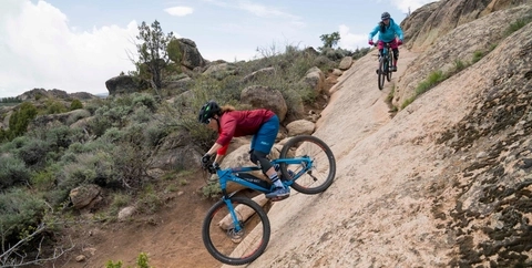 Mountain biker rides down a rock slab