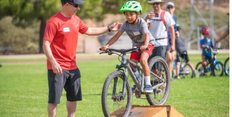 Kid riding a bike over a wooden feature