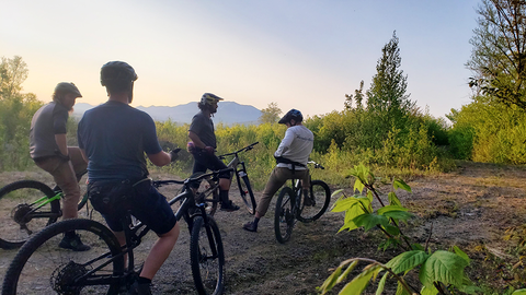 five mountain bikers pause while riding in Maine during sunset